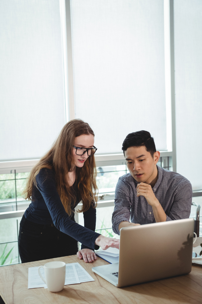 Photo of two people looking at a laptop and pointing.