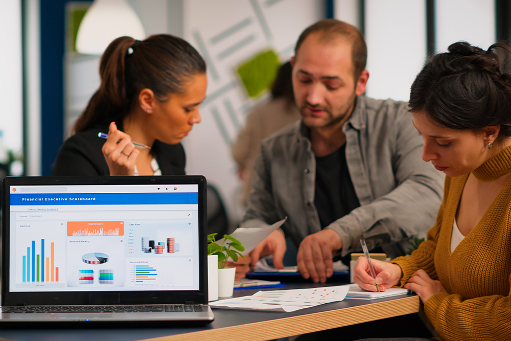 Photo of three professionals looking at a tablet in a bright office.