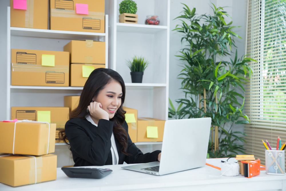 An Altselino staff member on a headset managing shipping boxes and laptop orders.