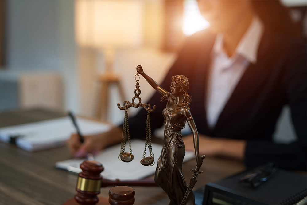 A legal professional at Altselino reviewing documents behind a Lady Justice statue.