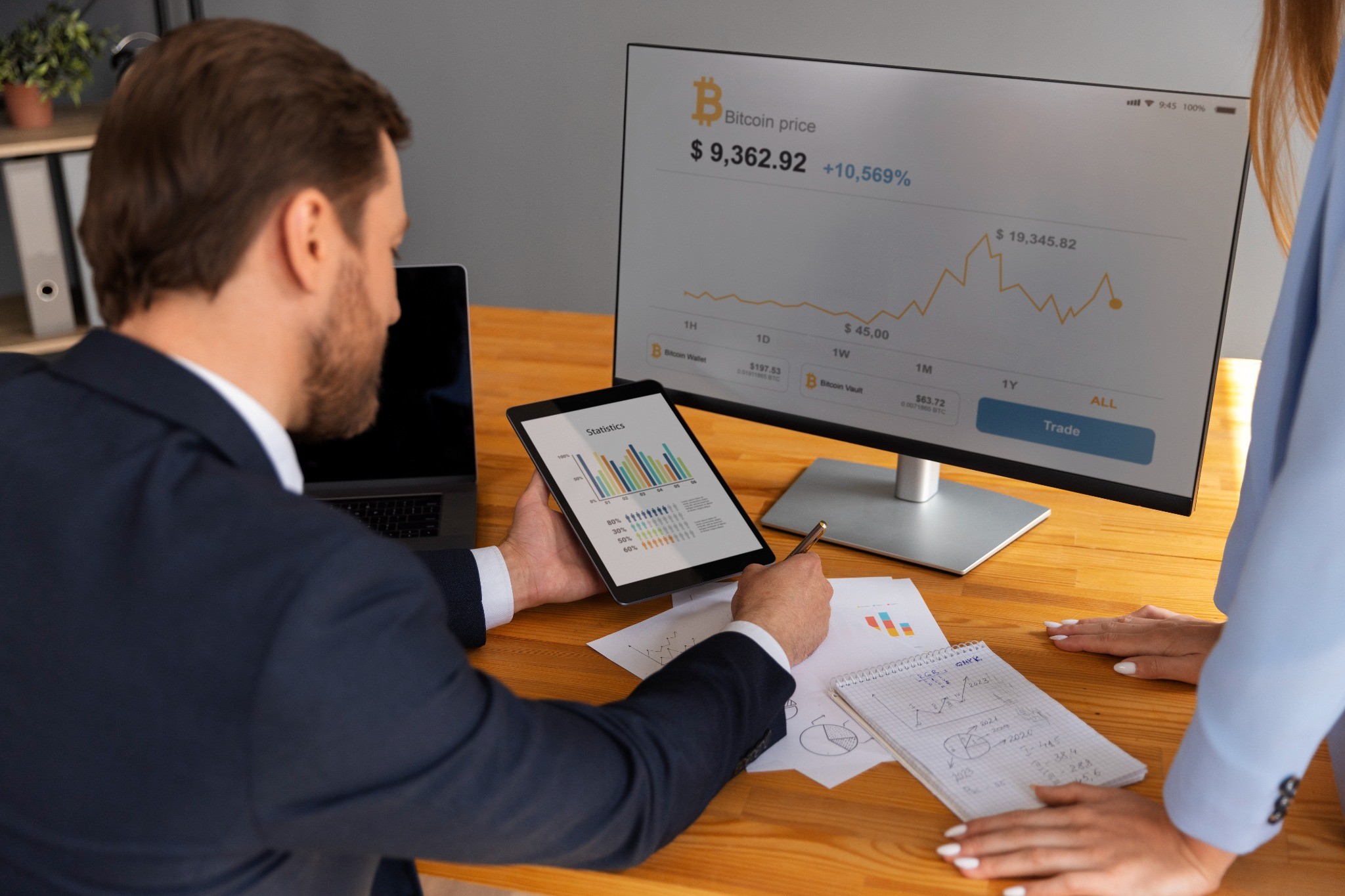 An executive reviewing data on a tablet and monitor with Altselino specialists.