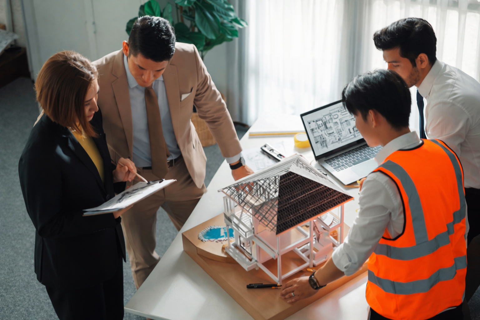 Altselino project managers reviewing a physical architectural model in an office.